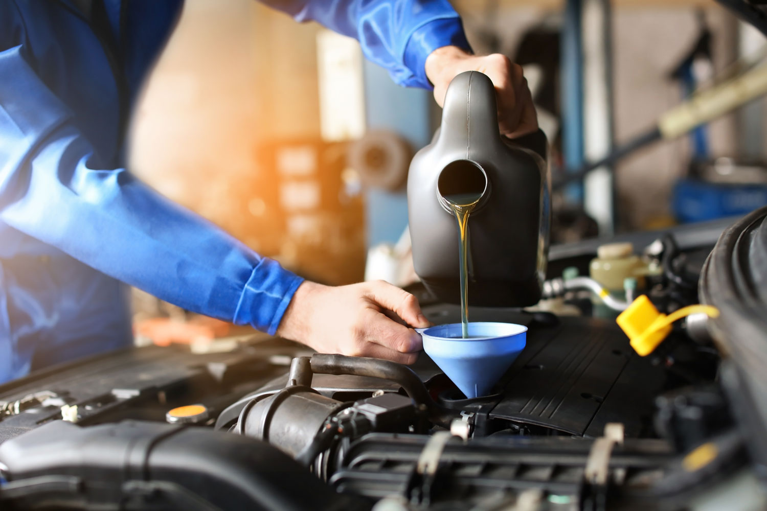Service technician hands pouring oil into a funnel