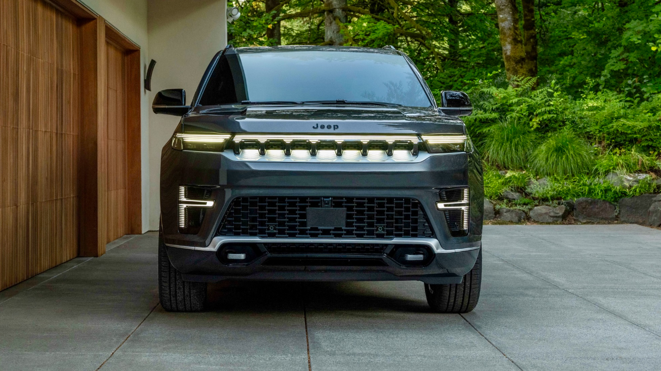 2026 Jeep Grand Wagoneer REEV parked outside of home with headlights on.